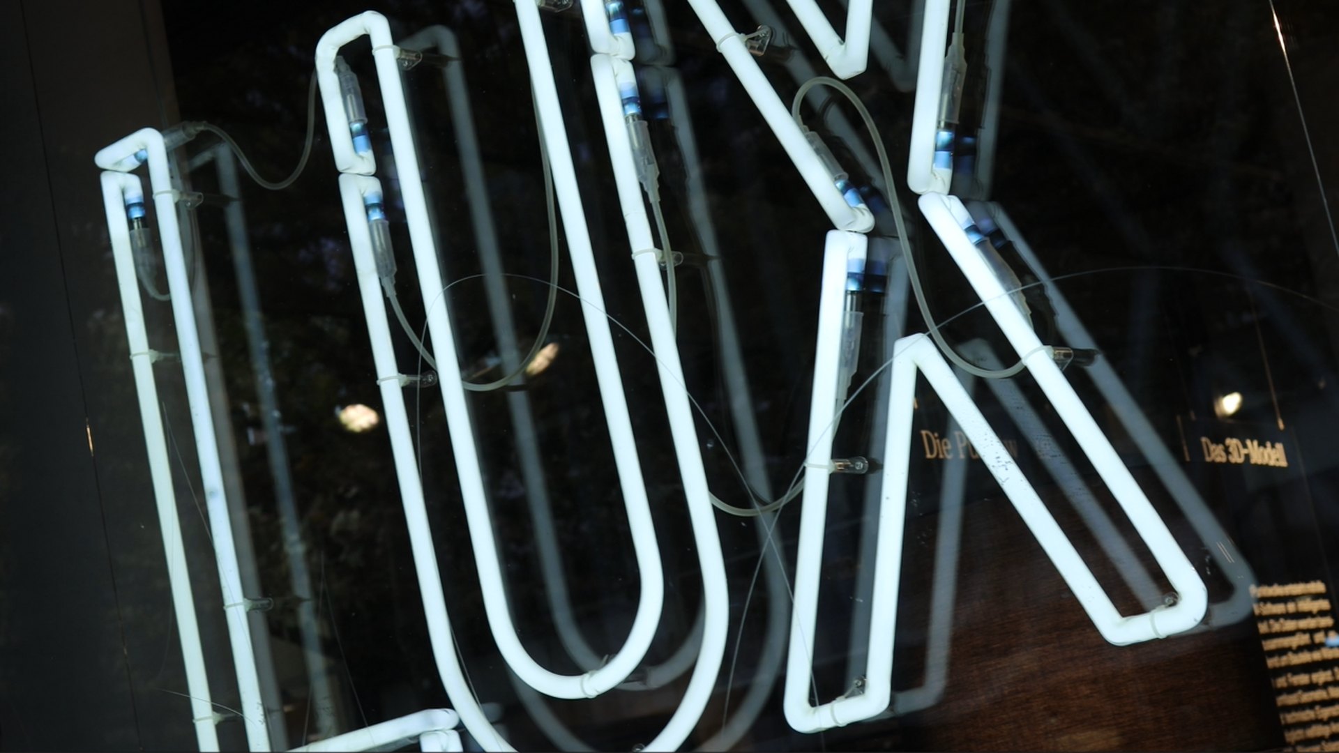 Standbild aus dem Showreel: Neonschriftzug LUX hinter Glas